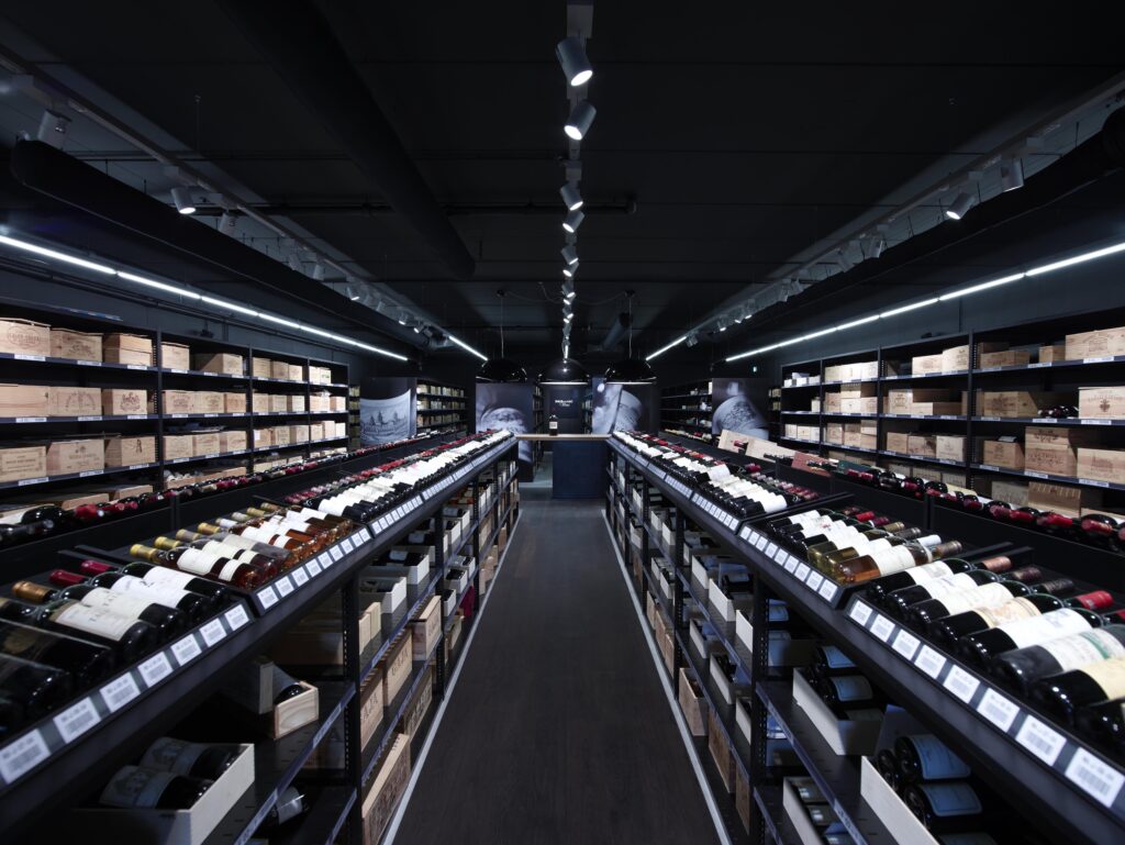 Weinkeller von Baur au Lac Vins mit einer exklusiven Auswahl an erlesenen Weinen, edlen Holzkisten und modernen Regalstrukturen. Stilvolle Beleuchtung hebt die hochwertigen Flaschen hervor und schafft eine elegante Atmosphäre.