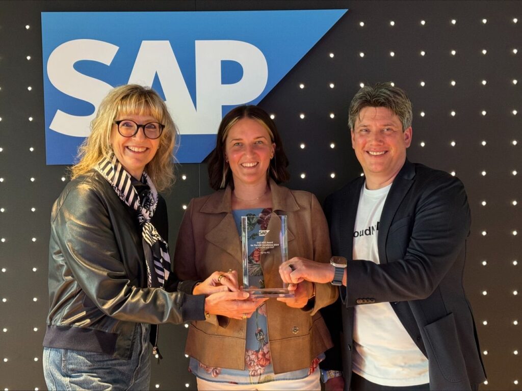 Drei Personen lächeln und präsentieren gemeinsam den SAP GROW Award vor einem beleuchteten SAP-Logo-Hintergrund.